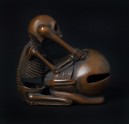 Netsuke in the form of a skeleton kneeling in front of a mokugyō, a Buddhist percussion instrument