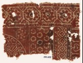 Textile fragment with rosettes in dotted frames, linked diamond-shapes, and Arabic inscription