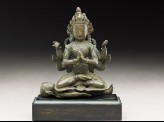 Seated figure of a crowned deity with four arms upon another figure