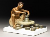 Model depicting a potter turning a pot on a wheel