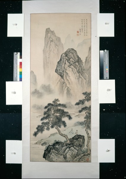 View of mountains with figures seated by a riverfront