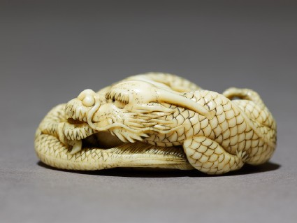Netsuke in the form of a dragon coiled around a bowlside