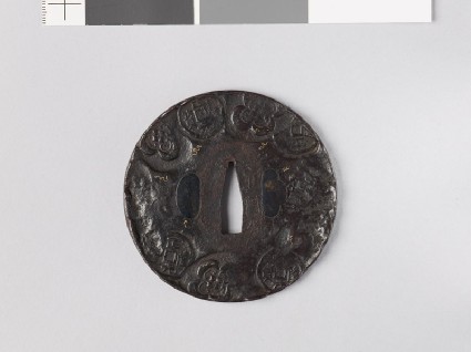 Round tsuba depicting old Chinese coins among mokkō shapes and scrollsfront