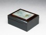 Box with plaque depicting a duck swimming past reeds (oblique)