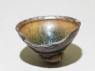 Black ware tea bowl with 'hare's fur' glazes, stuck to a firing pad (oblique)